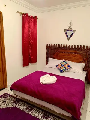 a bedroom with a large bed with a purple blanket at Maison Marrakech in Marrakech