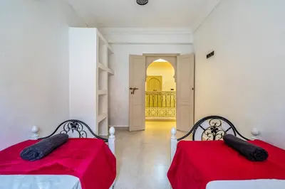two beds in a room with red sheets at New Stylish Riad - 4BR with Pool Access in Marrakech
