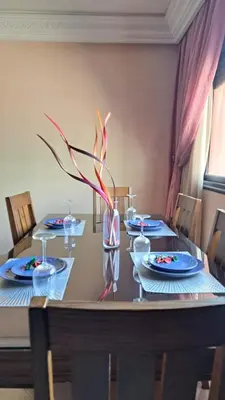 a dining room table with blue plates and a vase at Appartement tres aimable in Marrakech