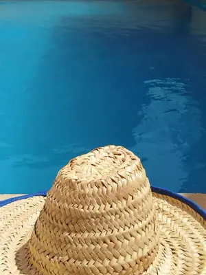 a straw hat sitting next to a swimming pool at Villa cosy & pool Marrakech in Marrakech