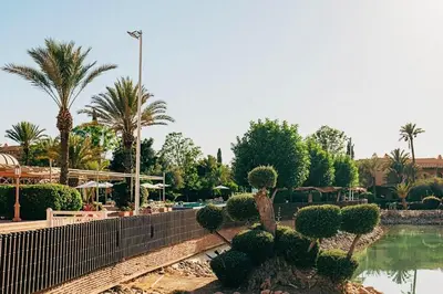 a resort with a pool and palm trees and a fence at Palmeraie - Open Garden & Pool in Marrakech