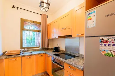 a kitchen with wooden cabinets and a refrigerator at Palmeraie - Open Garden & Pool in Marrakech