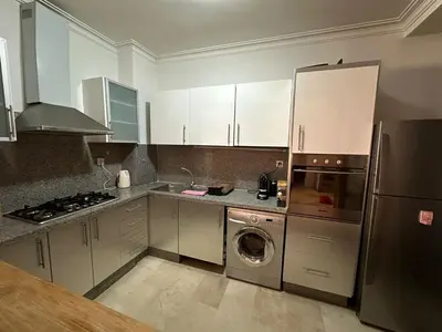 a kitchen with white cabinets and a washer at Appartement chaleureux au cœur de Marrakech in Marrakech