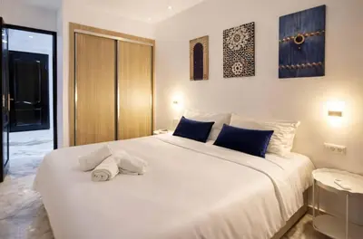a bedroom with a large white bed with blue pillows at Appartement 2 chambres à Guéliz avec terrasse et parking in Marrakech