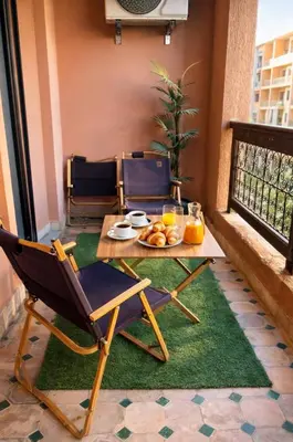 a table and chairs with a plate of food on a balcony at Appartement 2 chambres à Guéliz avec terrasse et parking in Marrakech