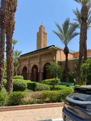 a car parked in front of a building with a clock tower at Youssef House Le Village Touristique in Marrakech