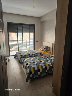 a bedroom with two beds and a large window at APPARTEMENT à TARGA in Marrakech