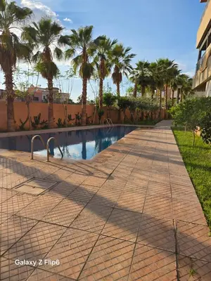 a sidewalk with palm trees and a swimming pool at APPARTEMENT à TARGA in Marrakech