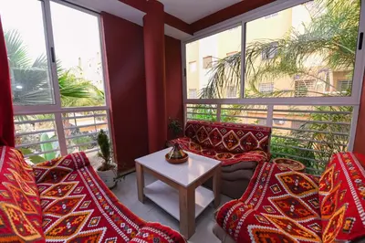 a balcony with red chairs and a table and windows at Jardin de chrifia cosy in Marrakech