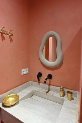 a bathroom with a bath tub with a round mirror at Suite Safran - Ambiance berbere in Marrakech