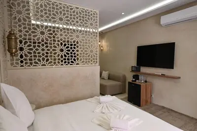 a hotel room with a bed and a flat screen tv at Suite Ivoire - Elegance a Gueliz in Marrakech