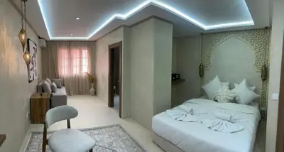 a bedroom with a white bed and a chair at Suite Dune - Confort et Elegance in Marrakech