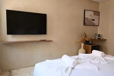 a bedroom with two beds with a television on the wall at Suite Oxyde - Elegance douce in Marrakech