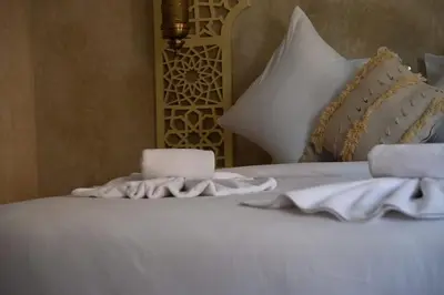 a white bed with a candle and towels on it at Suite Oasis - cosy et moderne in Marrakech