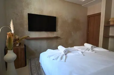 a bedroom with a bed with white sheets and a tv at Suite Atlas - Douceur et confort in Marrakech