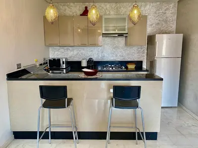 a kitchen with two bar stools and a refrigerator at Small 1-bedroom apartment perfect for discovering Marrakech in Marrakech