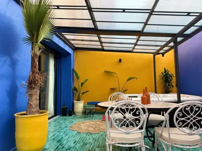a room with a table and chairs and palm trees at Beautiful winter apartment with private hot tub in Marrakech