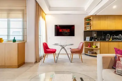 a living room with a table and two red chairs at City Center-1 Queen BR with AC, Pool and IPTV- Parking in Marrakech