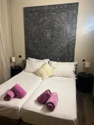 a bed with purple pillows on it with a large headboard at Duplex Le Vizir for 6 with Park Access 3 Pools in Dar Caïd Layadi