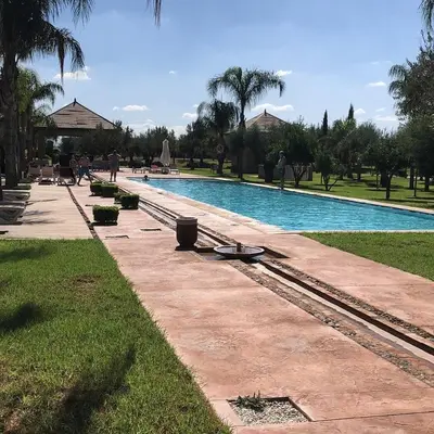 a swimming pool in a park with people walking by it at Duplex Le Vizir for 6 with Park Access 3 Pools in Dar Caïd Layadi