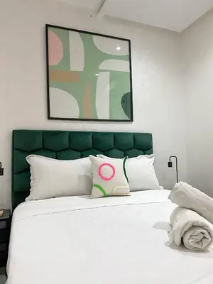 a bedroom with a white bed with a green headboard at Moulay Youssef in Marrakech