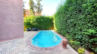 a swimming pool in a garden with a hedge at Villa Marrakech in Marrakech
