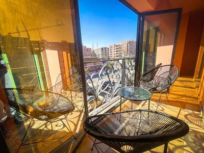 a balcony with chairs and tables on a balcony at Majorelle Cozy Apartment Garden 2-Balcony Downtown in Marrakech