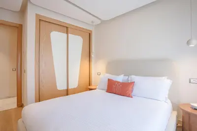 a bedroom with a white bed with a orange pillow on it at L'ambiance de Marrakech Luxe in Marrakech