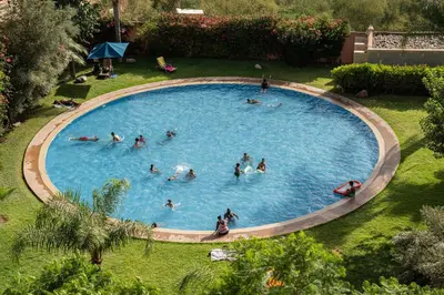 a group of people swimming in a large pool at Hivernage, piscine & jardin privé in Marrakech