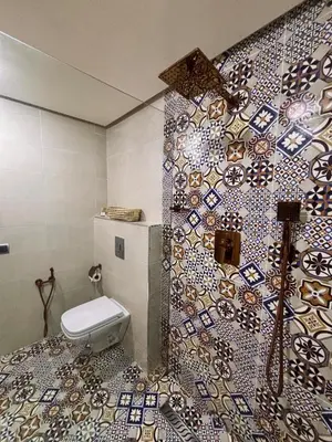 a bathroom with a toilet and a tiled wall at DAR ZINA - Heart of Medina, Marrakech in Marrakech