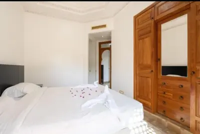 a bedroom with a white bed and a wooden cabinet at Palmeraie Village 2 in Marrakech