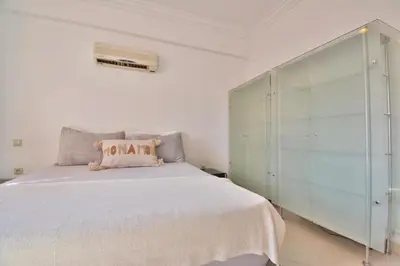 a bedroom with a white bed and a glass cabinet at Appartement Les Huit Palmiers in Marrakech