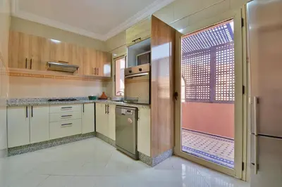 a kitchen with wooden cabinets and a sliding glass door at Appartement Les Huit Palmiers in Marrakech