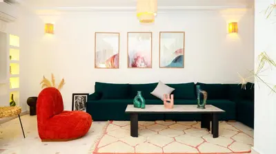 a living room with a green couch and a red chair at Riad Reflet D'orient Marrakech in Marrakech