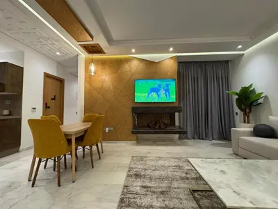 a living room with a table and a television on a wall at Luxury Retreat 2Bdr Appartment In Prime Marrakech in Marrakech