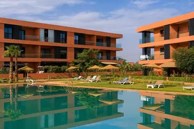 a hotel with a swimming pool in front of a building at Amberdi Noria Apartment Marrakech in Marrakech
