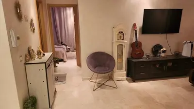 a living room with a chair and a television and a guitar at Achraf in Marrakech