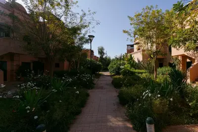 a brick path through a garden with flowers and trees at Atlas Golf Resort - piscine - rooftop in Marrakech