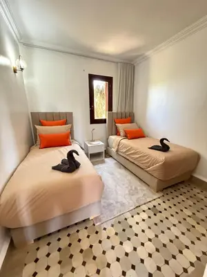 two beds in a room with orange pillows at Appartement La Palmeraie Marrakech in Marrakech