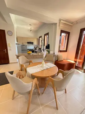 a living room with a table and chairs and a kitchen at Appartement La Palmeraie Marrakech in Marrakech