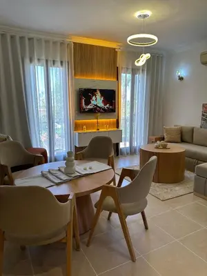 a living room with a table and chairs and a tv at Appartement La Palmeraie Marrakech in Marrakech