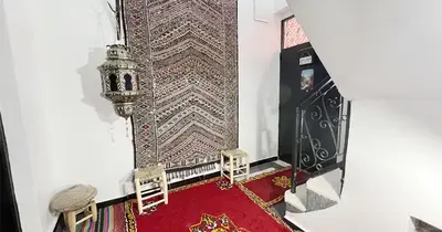 a living room with a red rug and a wall at Dar ESSEKIA in Marrakech