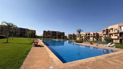 a large swimming pool in a park with buildings at Marrakech confort et détente à Argan Golf prestigia in Marrakech
