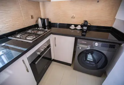 a small kitchen with a stove and a washing machine at Marrakech confort et détente à Argan Golf prestigia in Marrakech