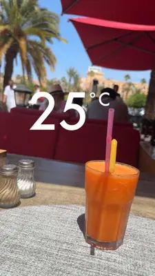 a glass of orange juice sitting on a table at Apt Marrakech vue sur Atlas in Marrakech