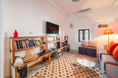 a living room with a couch and a tv at Dar KADO, Charming Hideaway in the Heart of Marrakech Medina in Marrakech