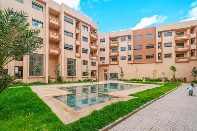 an apartment complex with a swimming pool in front of a building at 3 min de Guéliz - Appart avec balcon , vue piscine in Marrakech