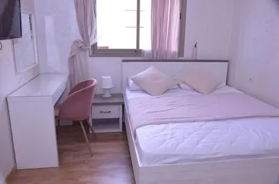 a white bedroom with a white bed and a desk at Appartement moderne in Marrakech