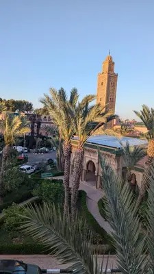 a view of a building with palm trees and a tower at Apartment lhaja in Marrakech