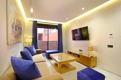 a living room with blue furniture and a tv at Heart of City 2BR 2Patios Fiber AC Modern New Calm in Marrakech